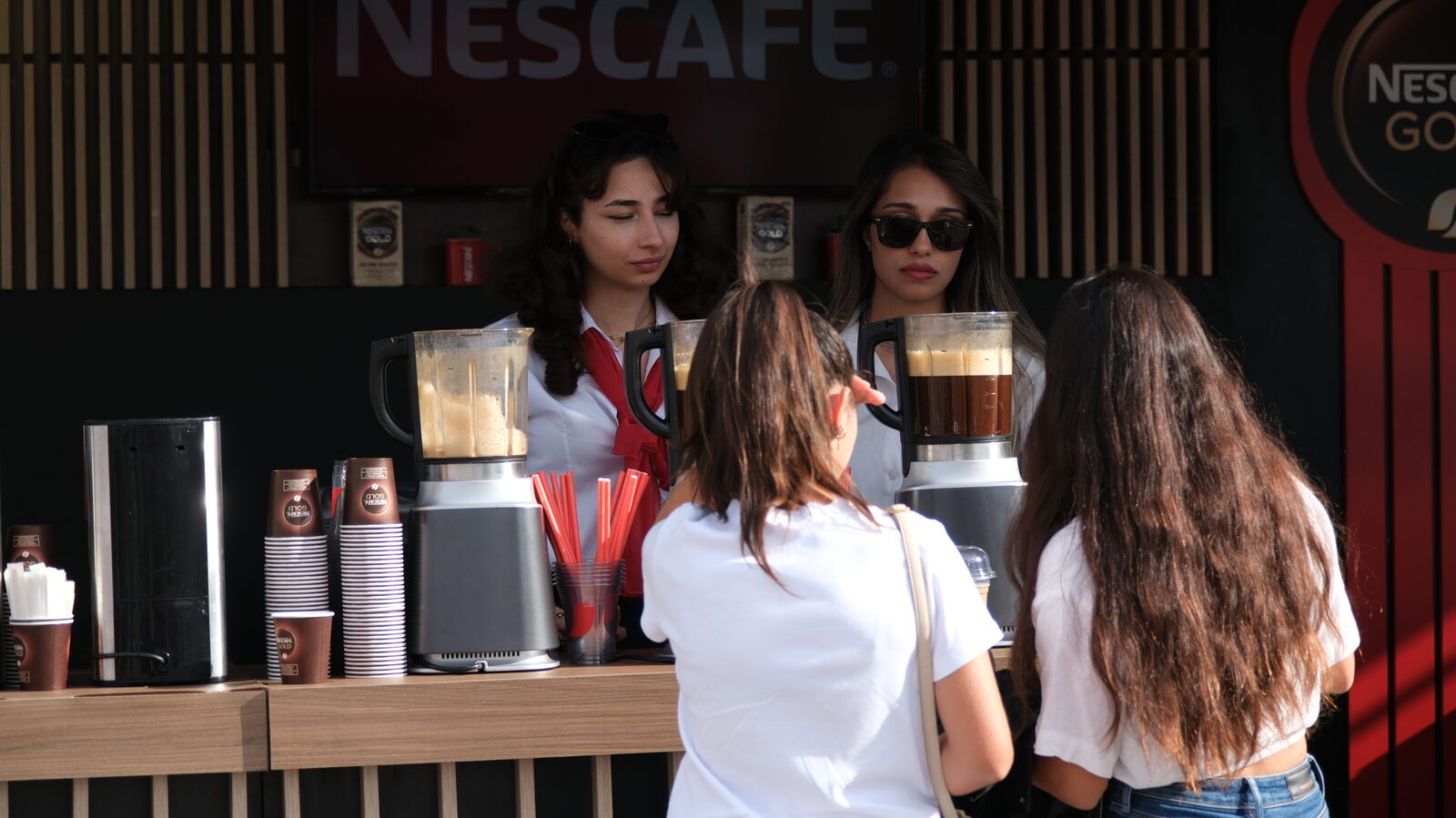 Visitors at a coffee counter, layered iced drinks lined up on the bar
