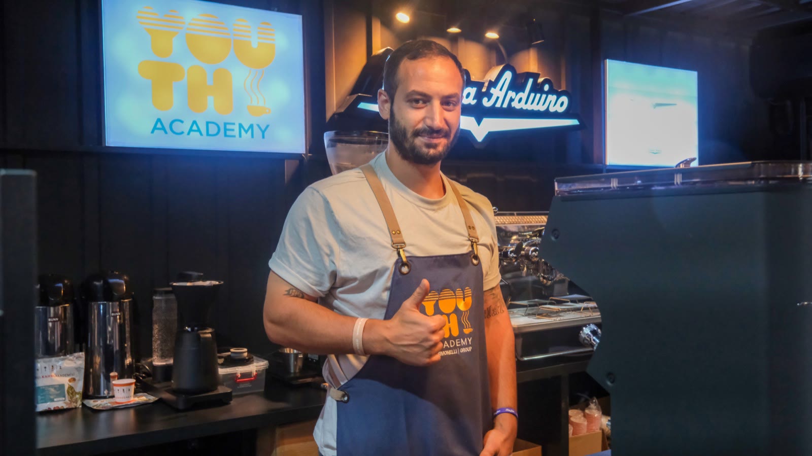 A barista in an apron in front of the espresso machine