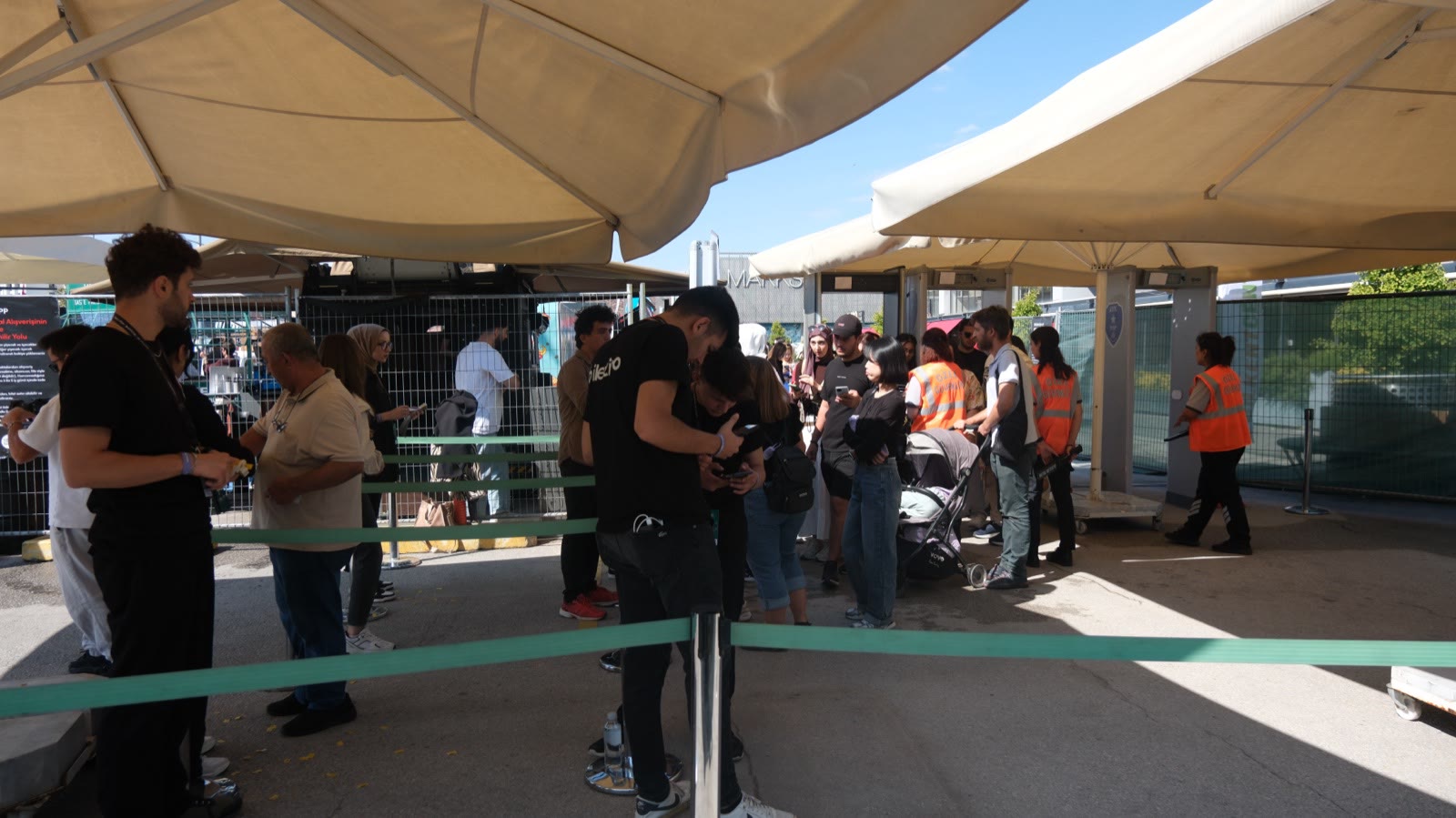 Visitors queuing at the entrance under white canopies