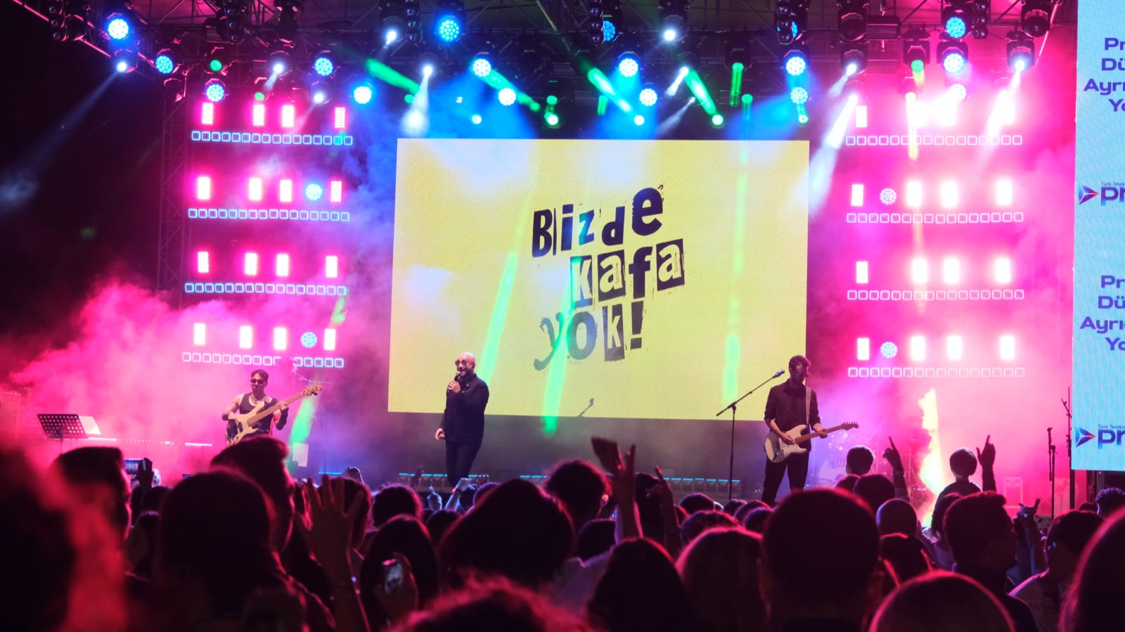 A band in front of a yellow LED wall, hands in the crowd