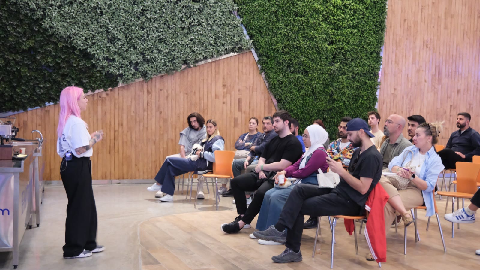 A talk in front of a living green wall, the audience seated