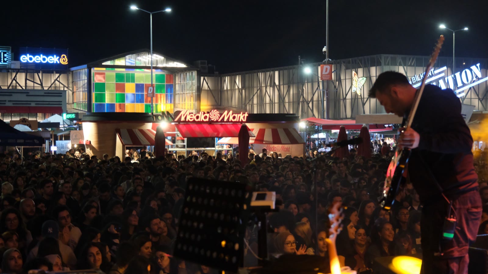 A guitarist on stage at night, the crowd below