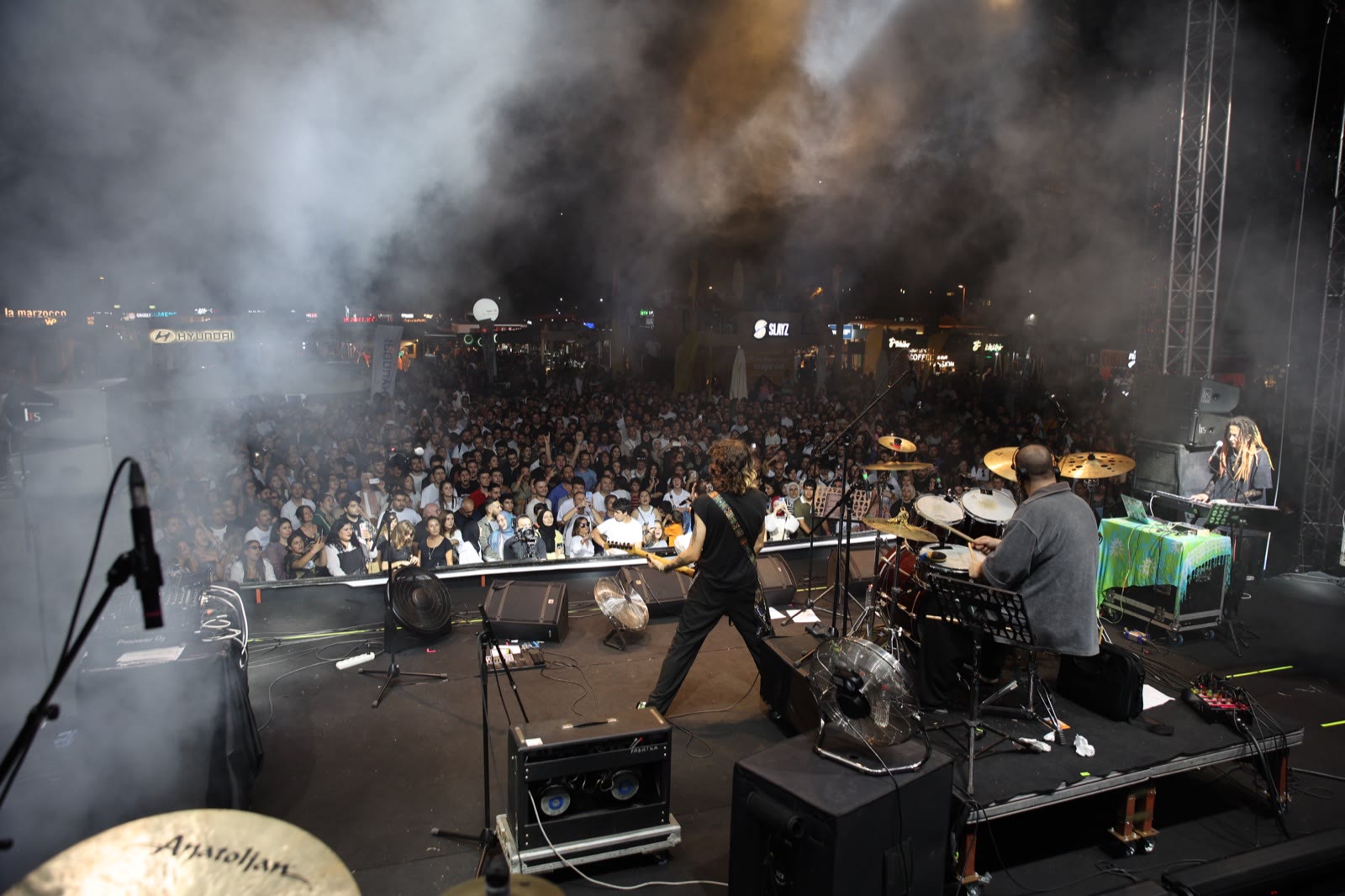 A band on stage in stage smoke, the crowd stretching to the back