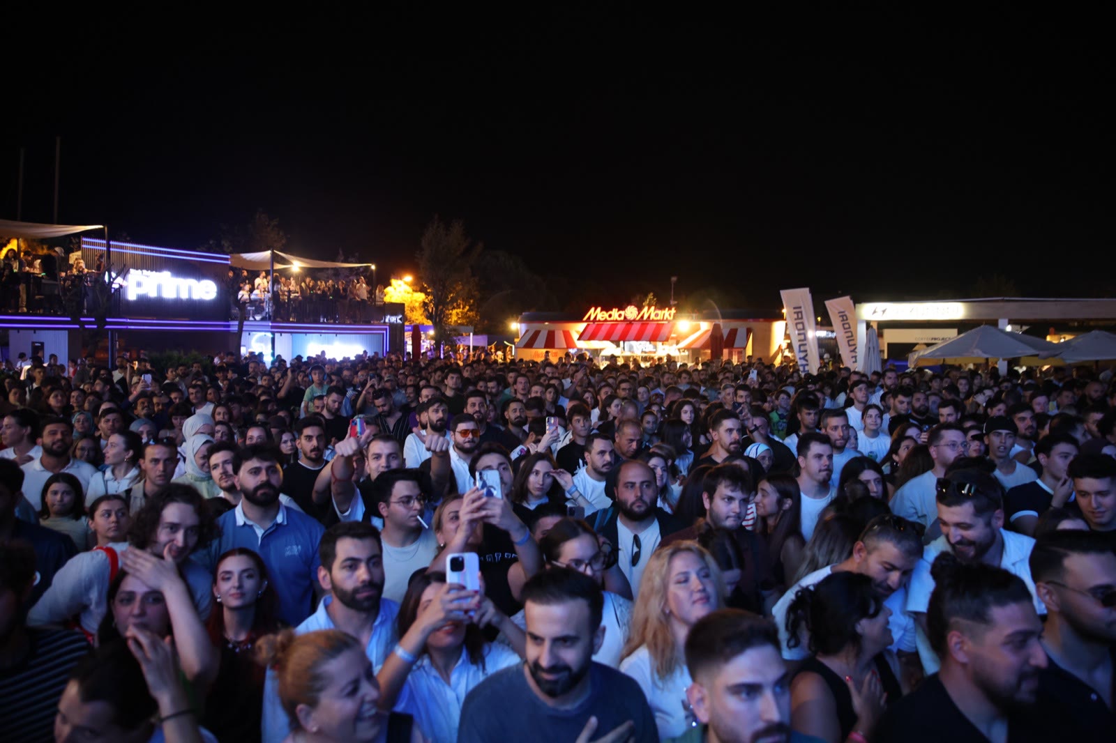 A crowd at night with the sponsor arch behind